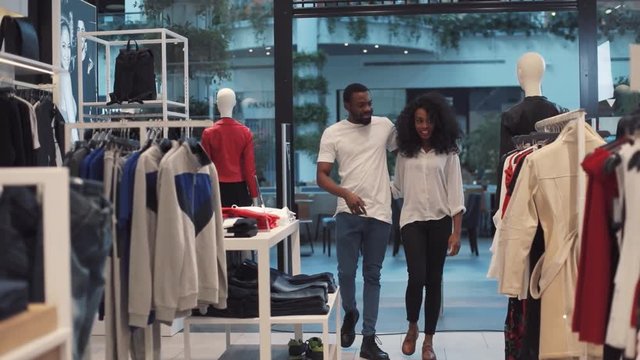 Young african american couple choosing clothes at clothing store walk smiling family woman fashion shopping man face style shop buyer look at camera boyfriend girlfriend slow motion close up