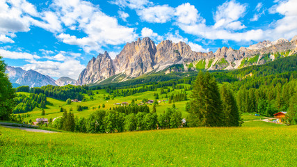 Rotsachtige bergkam van de Pomagagnon-berg boven Cortina d& 39 Ampezzo met groene weiden en blauwe lucht met witte zomerwolken, Dolomieten, Italië.