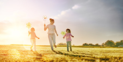 mother and two daughters are playing on meadow