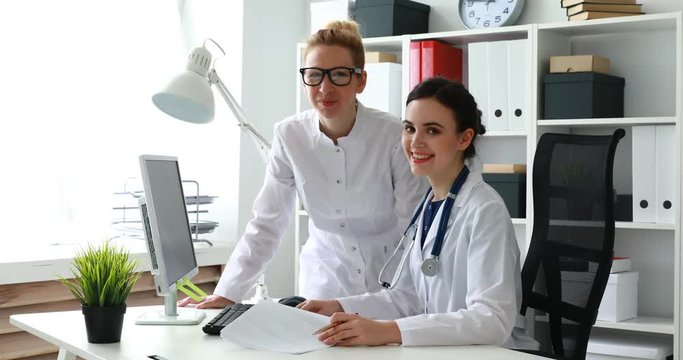 female smiling doctors looking at camera in light office.