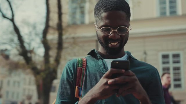 African American with glasses man using phone walking in city sunset technology businessmen busy people attractive modern black determined handsome lifestyle smartphone ambitious mobile movement