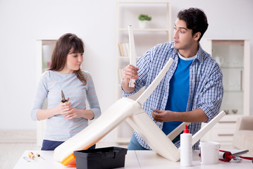 Wife helping husband to repair broken chair at home