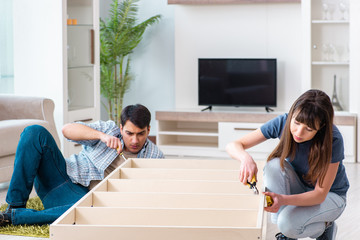 Young family assembling furniture at new house