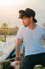Fototapeta premium Chico joven con smobrero mirando al horizonte con atardecer de fondo