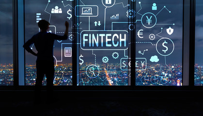Fintech theme with man writing on large windows high above a sprawling city at night