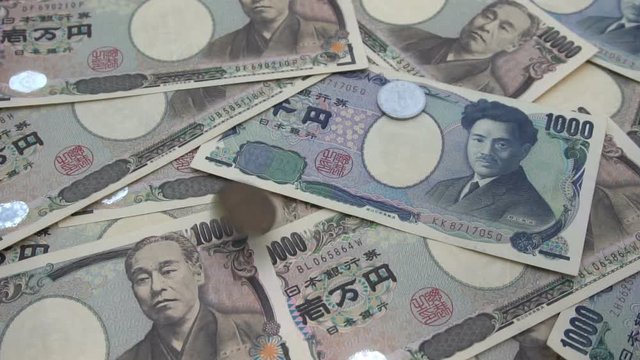 Close up of Japanese coin yen falling on banknotes 1000 and 10000 yen background. Super slow motion 120 fsp with sound.