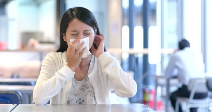 Woman suffer from flu and sneeze inside  restaurant