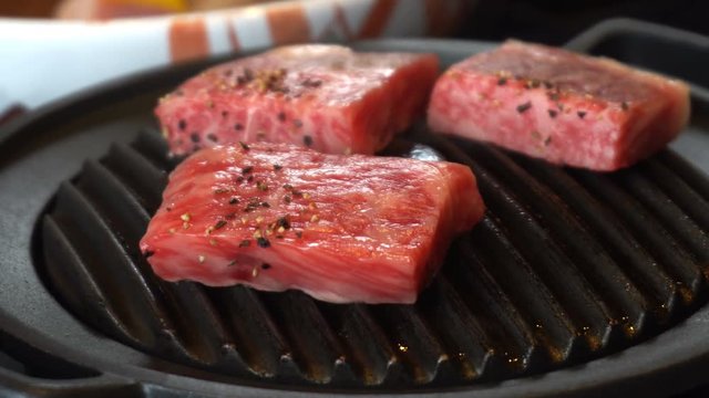 Cooking delicious juicy meat steaks on the grill on fire. Grillling premium beef Hida in Takayama Japan