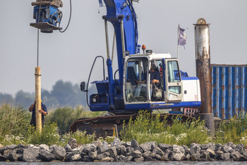 Hydraulic crane installing wooden bollard