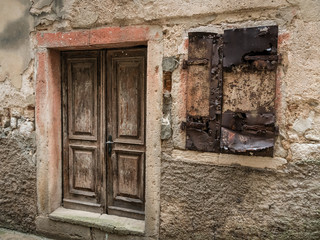 Fototapeta na wymiar Weathered old door and shutters of a stone house in Cres