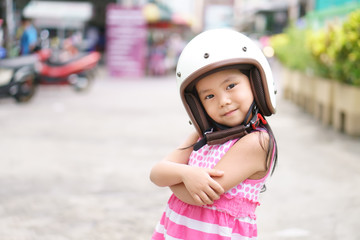 Asian children cute or kid girl smile wear classic white motorcycle or bike helmet with cross one's arm for confident and head safety or protect on street and road riding or driver travel with space