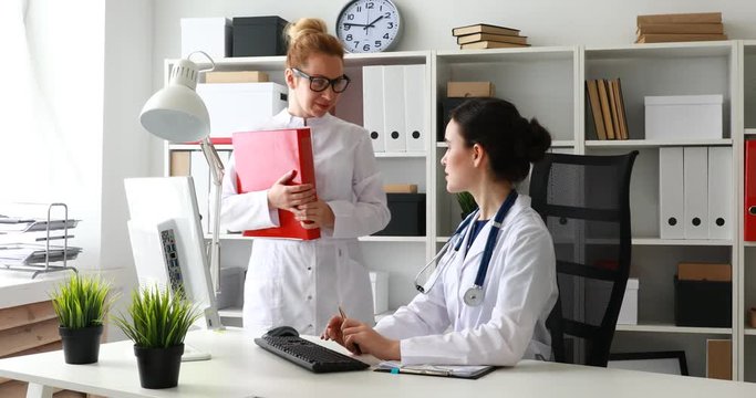 doctors discussing schedules on paper in office.