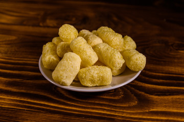Ceramic plate with corn sticks on wooden table