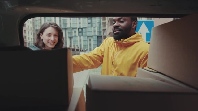 Smile courier African American open car gives a parce to a woman after signing on delivery device cardboard technology box order post postal service device sunny beard covered load logistic mailman