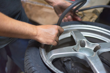 Closeup Of Mechanic At Repair Service Station inflating Tyre.