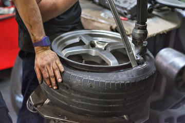 Professional mechanic using machine for tyre change.