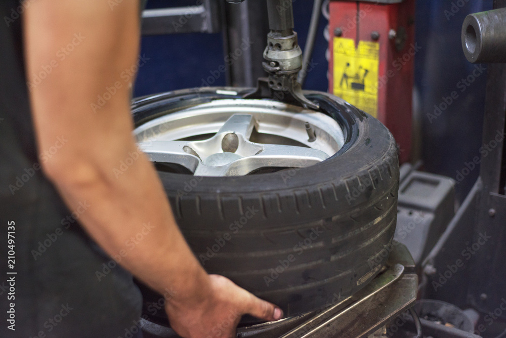 Wall mural Professional mechanic using machine for tyre change.