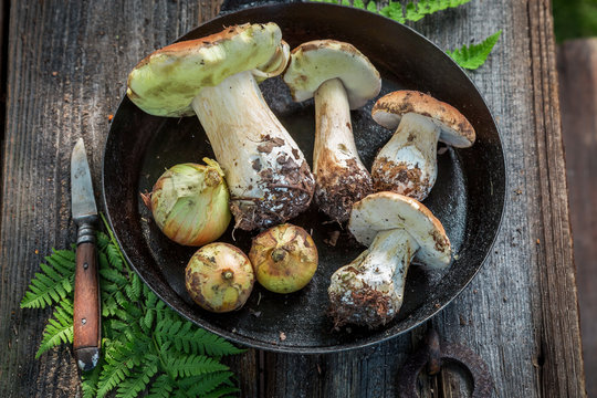 Fresh boletus mushrooms and onion on the pan