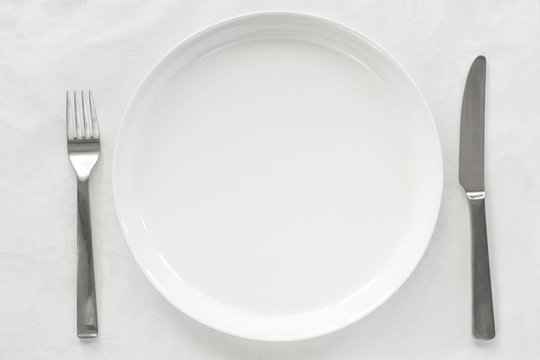 Empty White Plate on Brocade with Knife and Fork Top View