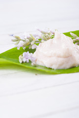 cosmetic cream on herbal leaf, white wood background
