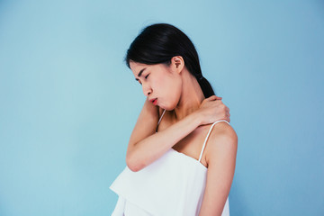 Fototapeta premium Young Asian woman having chronic neck and shoulder pain isolated over blue background - Healthcare and Medical concept