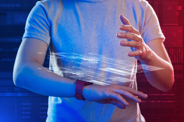Transparent hologram. Careful experienced IT manager standing with a smart watch on his wrist and putting his hand up while making a transparent hologram