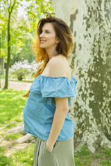 Pregnant woman enjoying in the park on spring summer day