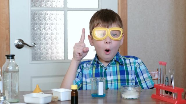 Experiments on chemistry at home. Insight or idea of a young scientist. Boy in plaid shirt and goggles.