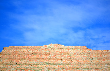 
wall of red brick shattered against the blue sky