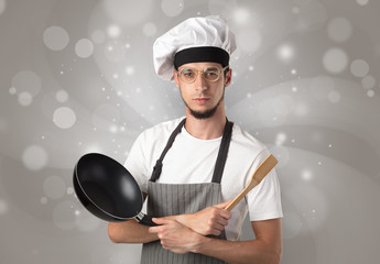 Male cook with kitchen tools and shiny grey wallpaper
