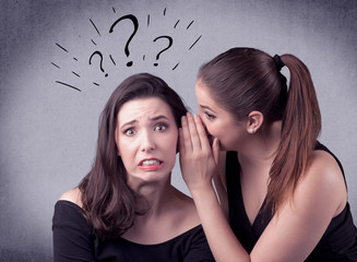 A teenager girl looking confused with drawn question marks above the head, while a girlfriend whispers something in her ear concept.