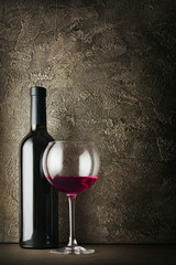 Red wine bottle and glass for tasting in dark cellar