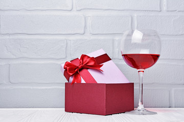 Glass with red wine for tasting and gift box for romantic surprise