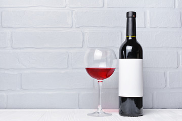 Red wine bottle with empty label and glass for tasting