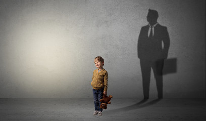 Little boy imagine that he will be businessman and illustrating his future in a big shadow
