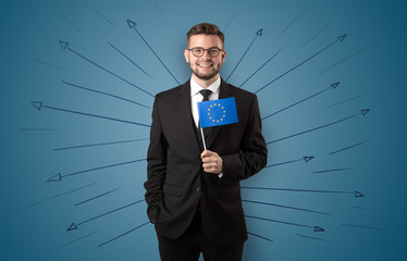 Smiling young man standing with flag and multidirectional arrows around
