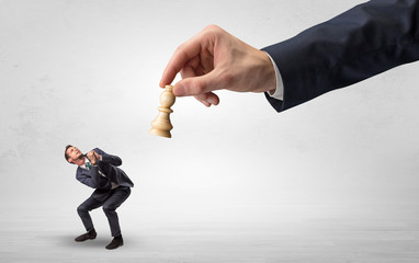 Big hand holding chessman and down little afraid businessman concept in a light space
