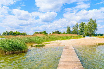 Fototapeta na wymiar Wooden pier on beach at Kryspinow lake near Cracow city on sunny beautiful summer day, Poland