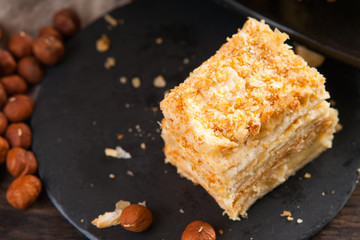 Slice of sweet classic layered cake Napoleon and hazelnuts 