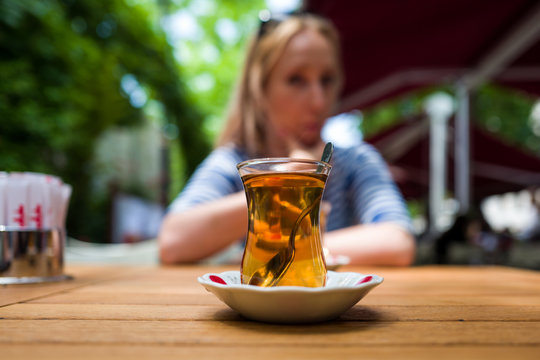 A glass of Turkish tea with girl in background