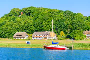 Sailing boat mooring in Baabe port and view of Moritzdorf village with houses on lake shore, Ruegen island, Baltic Sea, Germany