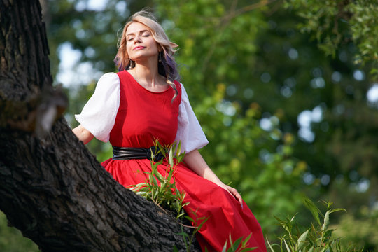 girl elf on a tree branch, in a red dress and a white blouse. resting