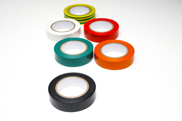 some rolls of colored insulating tapes on a white surface