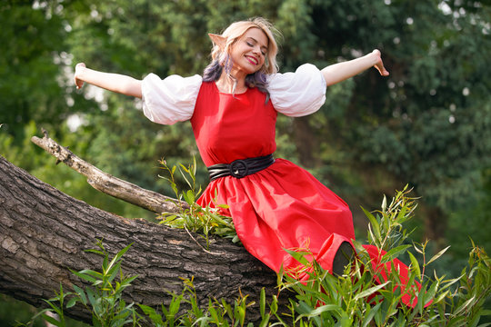 the girl on the tree branch woke up and stretched, in a red dress and a white blouse. resting