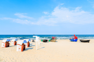 Traditional wooden chairs and fishing boats on sandy beach in Baabe summer resort, Ruegen island, Baltic Sea, Germany