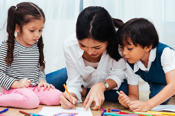 Family happy child kid girl kindergarten paint drawing on peper teacher education with mother mom