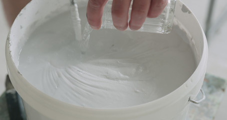 worker adding water into gray decorative concrete plaster