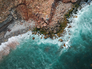 Aerial top view of sea waves hitting rocks on the beach with turquoise sea water. Amazing rock cliff seascape in the Portuguese coastline. © nvphoto