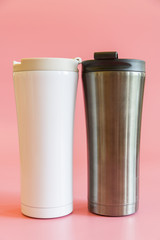 two insulated cups on a pink background. Thermo cup, thermo glasses. The concept of a hike and free life