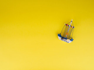 Vintage sailing boat ship on yellow. Wooden marine miniature, handmade souvenirs, minimalism is the concept of vacation